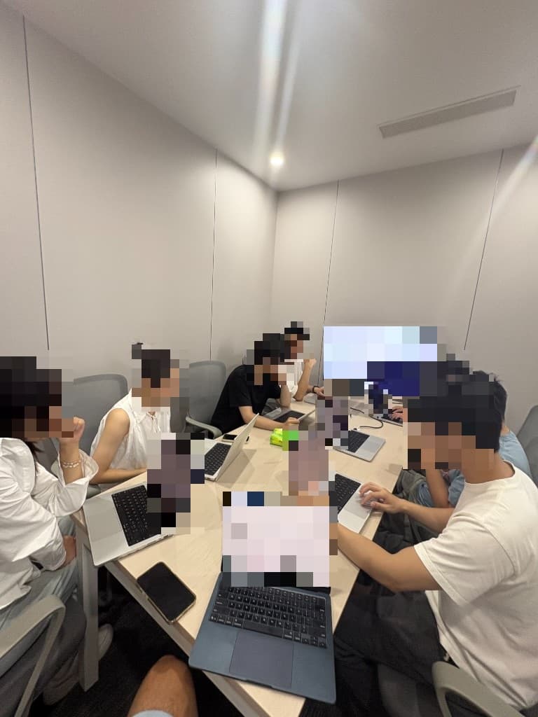 Engineers working together at a meeting-room table, faces pixelated